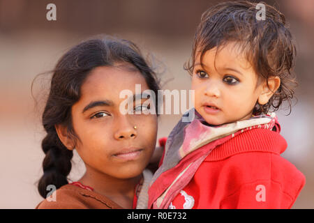 BHAKTAPUR, Nepal, November 25, 2010: Ein junges Mädchen hält ihre kleine Schwester auf dem Hauptplatz von Bhaktapur, Nepal. Stockfoto