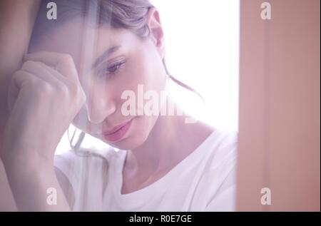 Junge Frau mit geschlossenen Augen Hände umklammern gegen die Fenster. Stockfoto