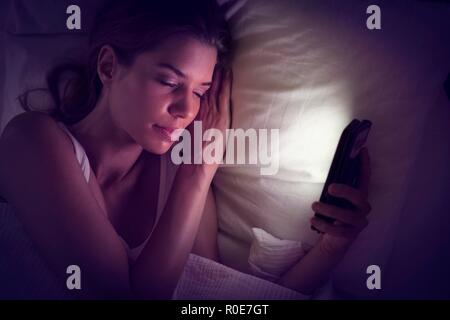 Junge Frau smartphone Holding im Bett und schlief. Stockfoto
