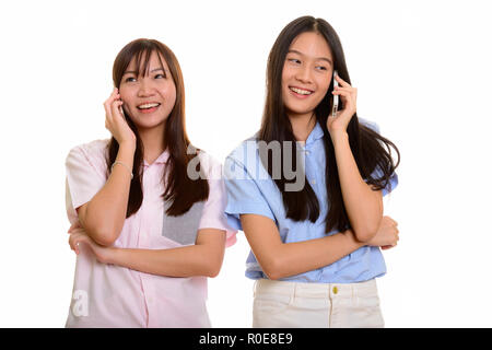 Zwei junge gerne asiatische Mädchen lächelnd und Sprechen auf Mobil Stockfoto