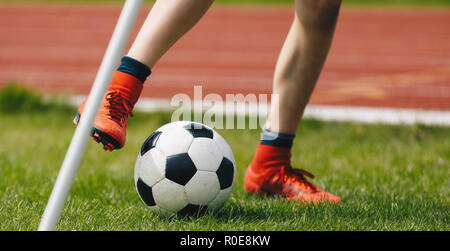 In der Nähe der jugendlichen Fußballspieler Kicking Kugel auf dem Fußballfeld. Fußball Eckball auf dem Spielfeld. Fußballer der Roten Stollen auf dem grünen Rasen der Sta Stockfoto