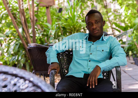 Jungen schwarzen afrikanischen Mann sitzt im freien Kaffee shop surrounde Stockfoto