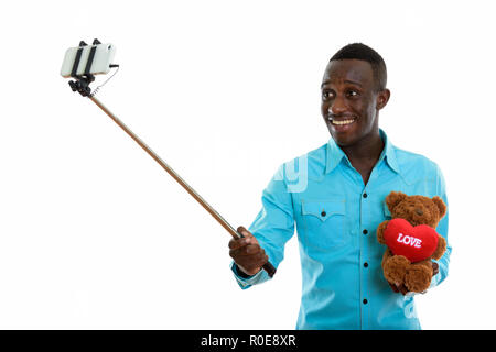 Junge glücklich schwarzer afrikanischer Mann und lächelnd Teddybär wit Stockfoto