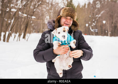 Tierbesitzer, Hund und Menschen Konzept - Young lächelnd kaukasischen Mann, hält Jack Russell Terrier im Freien im Winter. Stockfoto