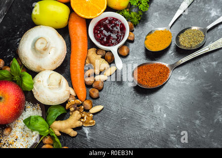 Bunte, gesunde Kräuter, Gewürze, Obst und Gemüse auf Schwarz, Tisch aus Stein Stockfoto