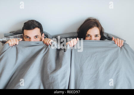 Liebevolle fröhliche Paar Blick von Decke, liegen zusammen auf dem Bett, glücklich nach der unvergesslichen Nacht, Ruhe im Schlafzimmer. Frau und Mann abgedeckt wit Stockfoto
