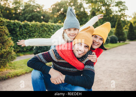 Hübscher junger Mann verbringt seine freie Zeit mit der Familie, erhält von entzückende Tochter und hübsche Frau umarmen, haben, Picknick im Herbst Wochenende. Glücklich Stockfoto