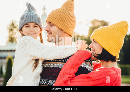 Menschen und Beziehung Konzept. Familie unvergessliche Zeit zusammen, embrae einander, Verschleiß trendy gestrickte Hüte. Adorable kleinen Mädchen mit pigtai Stockfoto