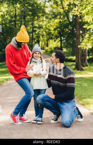 Adorable kleine niedliche Kind froh sein, die von den Eltern unterstützt werden, teilt ihre Gefühle nach dem Besuch der Kinder Garten, hat eine gute Entspannung im Park. Modell Stockfoto