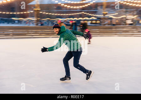 Männliche in der Geschwindigkeit zeigt seine Fähigkeiten der Skaten, hat Spaß am Ring, fühlt sich sicher und selbstbewusst auf Eis, freie Zeit im Freien verbringt, genießt, winter Urlaub, Stockfoto