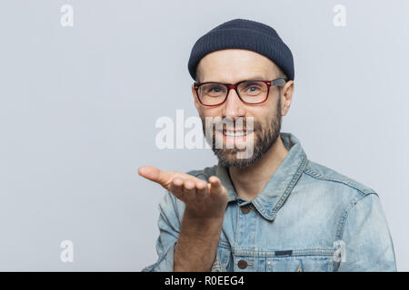 Froh, bärtigen Mann in modischen Brillen drückt seine Liebe, zeigt, kiss, hat freundliche Ausdruck, über grauer Hintergrund isoliert. Blue eyed mittleren Alters Stockfoto