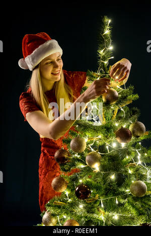 Junge Frau schmückt den Weihnachtsbaum. Elf und mit Dekorationen aus Fichtenholz. Mädchen und schmücken. Stockfoto