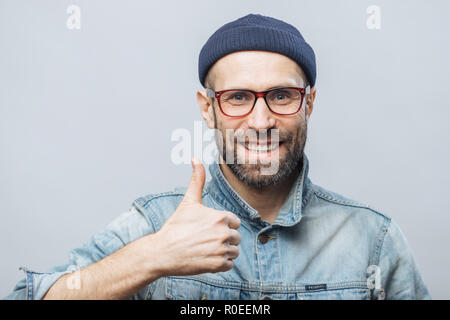 Portrait von froh, dass Männer mittleren Alters mit dicken Bart und Schnurrbart zeigt seine Zufriedenheit mit etwas, hebt den Daumen, hat positive Lächeln im Gesicht, isol Stockfoto