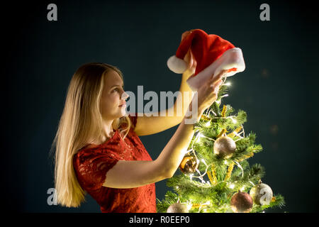 Junge Frau schmückt den Weihnachtsbaum. Elf und mit Dekorationen aus Fichtenholz. Mädchen und schmücken. Stockfoto