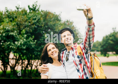 Lächelndes Paar ihre freie Zeit genießen, wodurch selfie, in Kamera posieren, umarmen einander, mit wunderschöner Natur und gute Stimmung. Entspannt Stockfoto