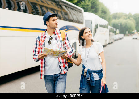 Die jungen wandern Paar durch Big City gehen, aufmerksam zur Seite suchen, mit City Guide für die Exploration neuer Orte auf der Karte. Familie Paar journe Stockfoto