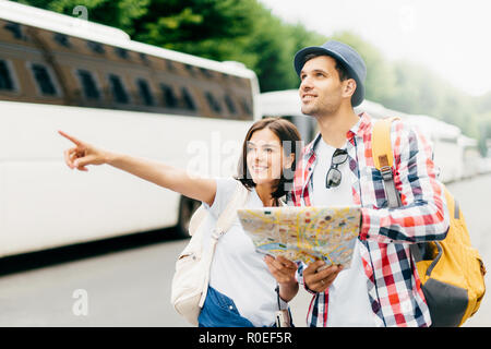 Glückliche junge touristische Rucksacktouristen auf der Suche nach Richtung, auf der Suche nach Ort, wo zu gehen. Europäisches paar Ferien im Stadtplan suchen, pointin Stockfoto