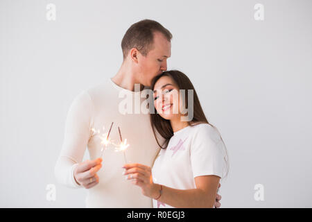 Valentinstag Konzept - Junge glücklich lächelnde Fröhliche attraktive Paare feiern mit Wunderkerzen auf weißem Hintergrund Stockfoto