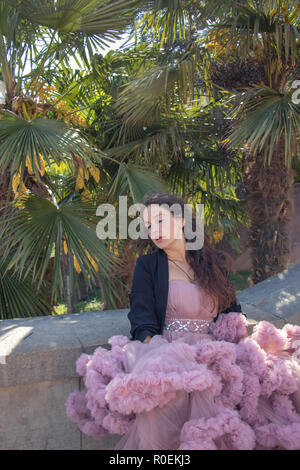 Schöne hipster Girl in einem rosa Ballsaal Kleid mit Palmen im Hintergrund gekleidet Stockfoto