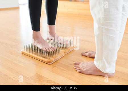 Mutige Frau, die auf dem Bett der Nägel bei Yoga Praxis Stockfoto