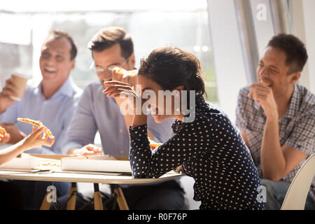 Indische Frau lachend essen Pizza mit verschiedenen Kollegen in aus Stockfoto