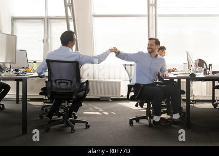 Freundliche männliche Freunde Faust stoßen bei der Arbeit feiern Gute teamwo Stockfoto