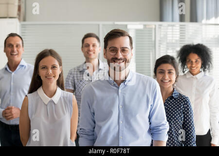 Lächelnd ceo bei Kamera schaut im Büro mit Team Stockfoto