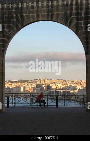 Valleta, Malta - Mai 2018: Mann auf Bank in Arch im Lower Barrakka Gardens sitzen bei Sonnenuntergang Stockfoto