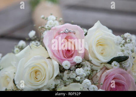 Engagement Ring sitzen in der Bräute Hochzeit Bouquet von rosa- und Cremefarbenen Rosen Stockfoto