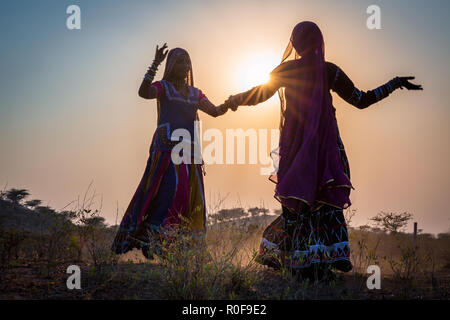 Silhouetten der beiden gypsy Frauen tanzen bei Sonnenuntergang, Pushkar Camel Fair, Pushkar, Rajasthan, Indien Stockfoto
