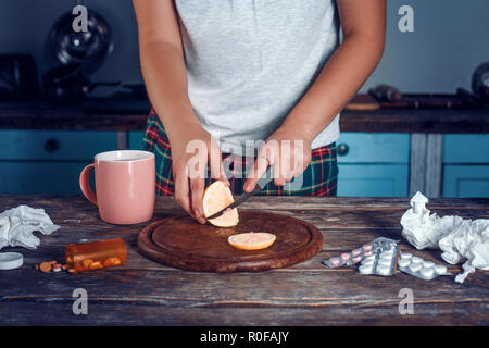 Blick auf die Hände schneiden Zitrone auf Carving Board Stockfoto