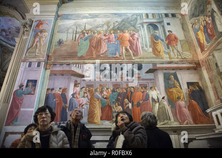 Asiatische Besucher nehmen Sie an einer Führung in der Brancacci Kapelle (Cappella Brancacci) in der Kirche von Santa Maria del Carmine in Florenz, Toskana, Italien. Fresken von italienischen Renaissance Maler Masaccio (1420-1427) abgeschlossen von Filippino Lippi (1485) sind im Hintergrund zu sehen. Stockfoto