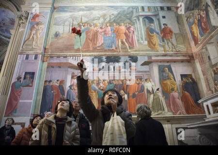 Asiatische Besucher nehmen Sie an einer Führung in der Brancacci Kapelle (Cappella Brancacci) in der Kirche von Santa Maria del Carmine in Florenz, Toskana, Italien. Fresken von italienischen Renaissance Maler Masaccio (1420-1427) abgeschlossen von Filippino Lippi (1485) sind im Hintergrund zu sehen. Stockfoto