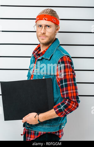 Verhaftet hipster Mann in Brillen und Kopfbügel Holding leer Gefängnis vor Polizei Line up Stockfoto