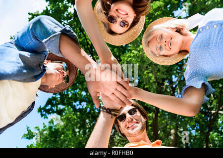 Ansicht von unten auf das Multiethnische lächelnden Freunde halten sich an den Händen zusammen Stockfoto