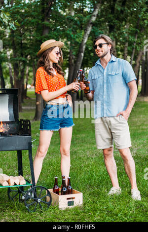 Stilvolle Paar klirrenden Flaschen Bier während der Grill im Park Stockfoto