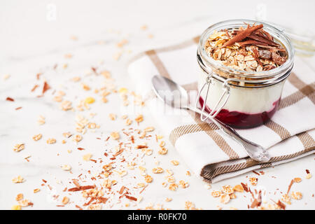 Gesundes Frühstück. Jar Gesunder Joghurt mit Erdbeersauce, Hafer und Schokolade auf weißem Marmortisch. Schließen oben mit kopieren. Stockfoto