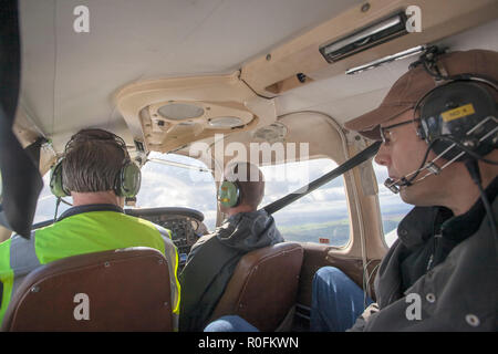 Pilot, Co Pilot und Passagier in einem Piper PA-28 Cherokee Leichtflugzeug aus Northumbria Flugschule, Flughafen Newcastle, Tyne fliegen und Verschleiß, Großbritannien Stockfoto