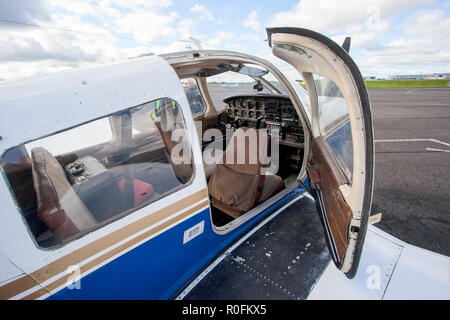 Eine Tür geöffnet und zeigt die Instrumententafel eine Piper PA-28 Cherokee Light aircraft von Northumbria Flugschule, Flughafen Newcastle, Tyne und Wear, Großbritannien Stockfoto