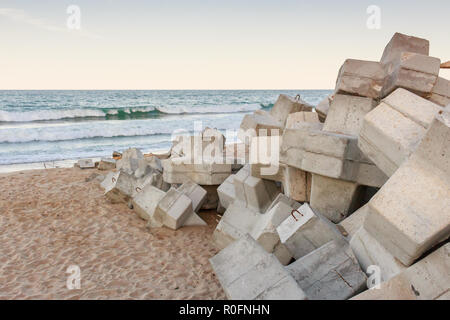 Wellenbrecher mit betonsteine auf Sand Strand, Sonnenuntergang Stockfoto