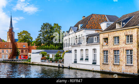 Mädchen sitzen in einem offenen Fenster mit einem modernen Mobiltelefon in einem historischen Backsteingebäude auf der Sint Annarei Kanal in der mittelalterlichen Stadt Brügge, Belgien Stockfoto