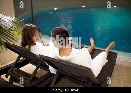 Zwei liebende Paare in bademänteln Sitzen am Pool Stockfoto