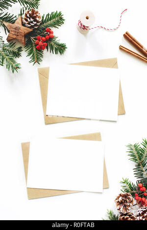 Weihnachten Komposition. Leere Grußkarte, Umschlag Mock-up-Szene. Tannenzapfen, Fir Tree Branches, rote Vogelbeeren und hölzernen Sterne auf weißem Hintergrund. Flach, Ansicht von oben, senkrecht. Stockfoto