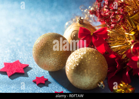 Wunderschöne Metallic gold Weihnachtskugeln, rote Sterne und auf glänzenden blauen Hintergrund verpackt präsentieren. Weihnachten Grenze. Stockfoto