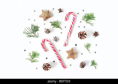 Weihnachten Komposition. Dekorative winter Muster, Banner aus Zypresse Äste, Tannenzapfen, Zuckerstangen, Anis, Holz- und silber Konfetti Sterne. Weißem Hintergrund. Flach, Ansicht von oben. Stockfoto