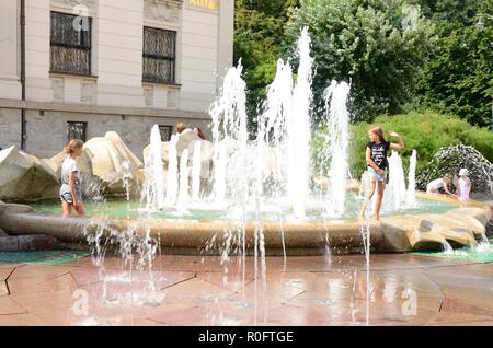 Krakau, Polen - 25. Juli 2018: Kinder spielen mit Wasser an einem Sommertag am Brunnen in der Altstadt von Krakau, Polen. Stockfoto