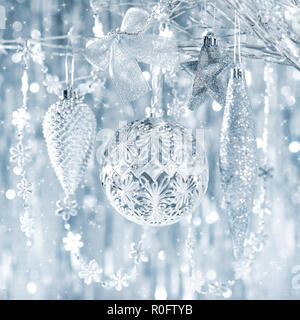 Glänzendes Silber Weihnachtsverzierungen Hängen an einem Baum, mit Defokussierten Weihnachtsbeleuchtung im Hintergrund. Stockfoto