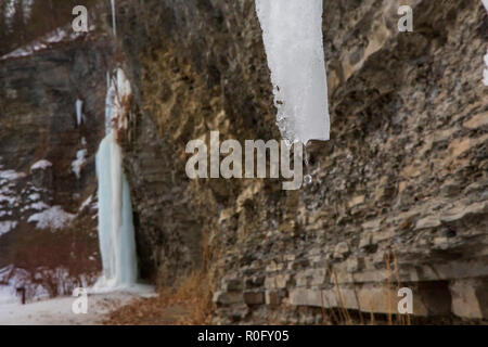 Gefrorenen Wasserfällen auf einer Klippe in Watkins Glen State Park, Watkins Glen, im Staat New York an einem sonnigen, aber kalten Wintertag. Stockfoto