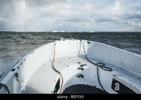 Ein kleines Boot segeln in der Ostsee mit Paldiski, Estland Hafen im Hintergrund. Dramatische Herbst Tag. Stockfoto