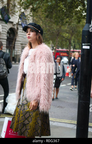 LONDON, Großbritannien - 14 September 2018: Leute auf der Straße, während der London Fashion Week. Mädchen in einer schwarzen Kappe rosa Fell aus Fellimitat und Sk Stockfoto